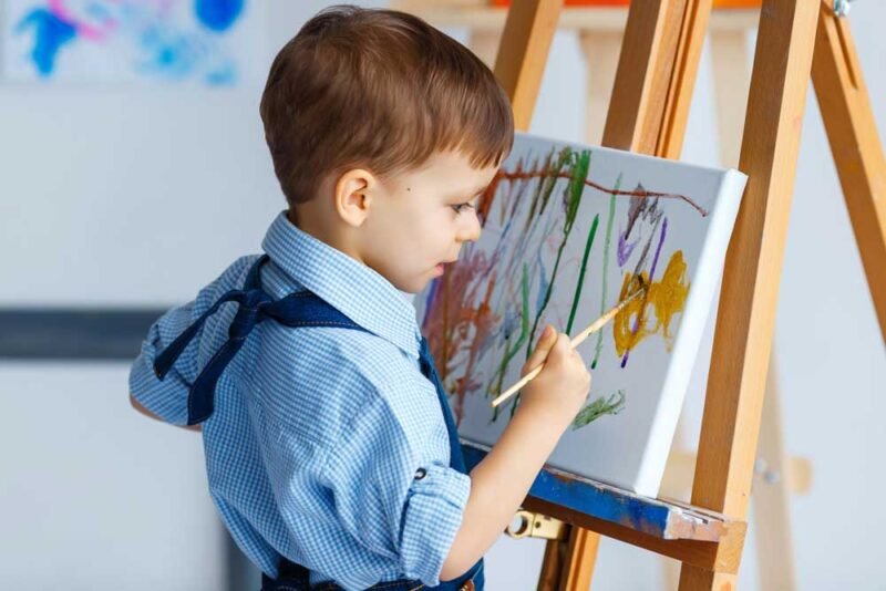 Cute, serious and focused, white three years old boy in blue shi