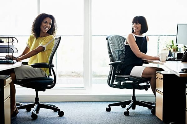 Two female coworkers laughing in a modern office